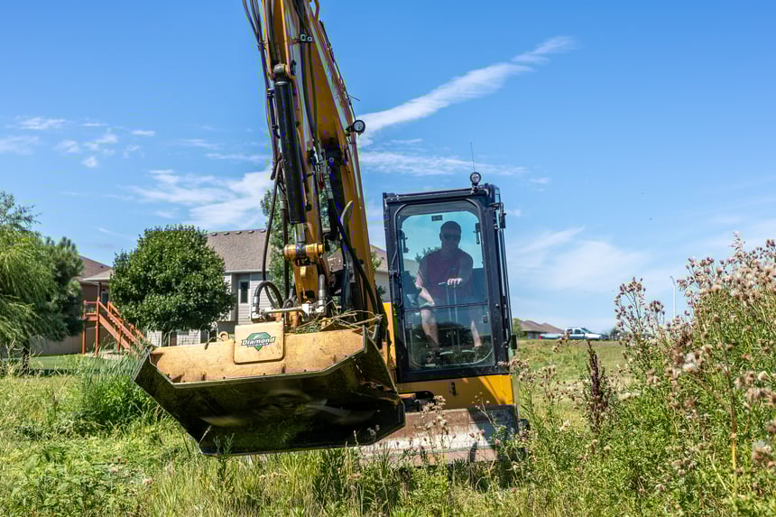 excavator with brush cutter cutting brush