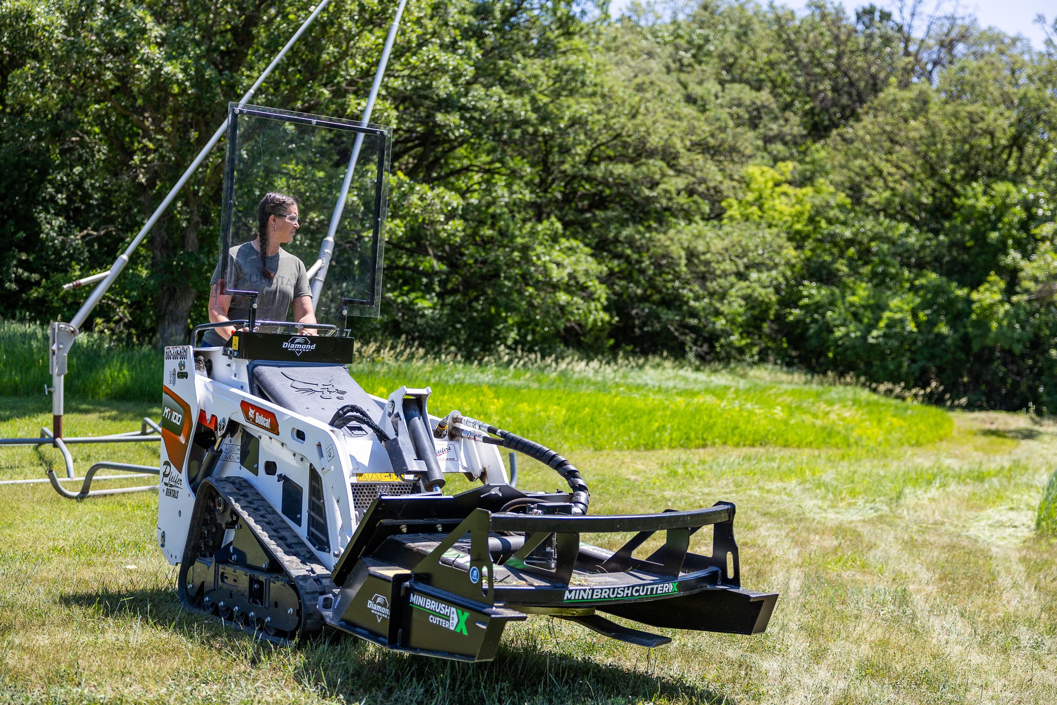 person driving a mini skid steer through a field
